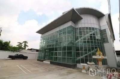 Warehouse for rent or sale in Prawet, Bangkok - Modern glass-front office and warehouse exterior with wide parking area in Prawet, Bangkok.