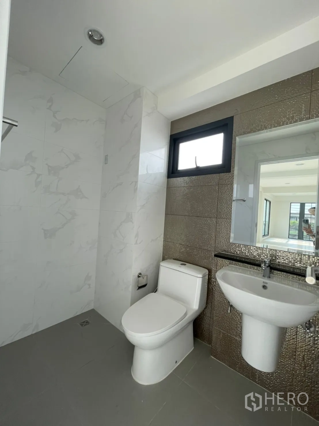 Home Office for rent in Suan Luang, Bangkok - Modern bathroom with white fixtures, marble-look wall tiles and a small window.