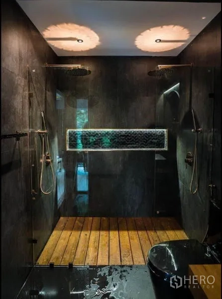 Townhouse for rent in Khlong Toei, Bangkok - Modern dark-tiled bathroom with dual rain showers, glass enclosure and wood slat floor.