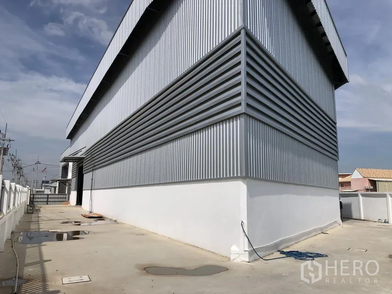 Factory for rent in Samut Prakan - Rear service walkway along the corrugated steel exterior of the building.