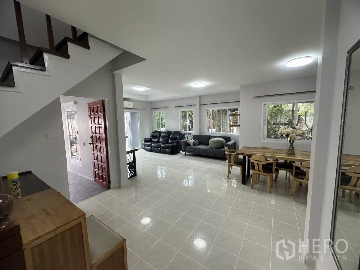 Townhouse for sale in Lam Luk Ka, Pathum Thani - Spacious living area with sofas, multiple windows and glossy tiled floor.