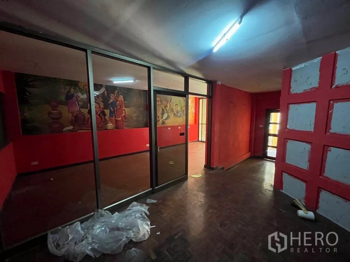 店屋 出租在Watthana, Bangkok - 开放区域，落地玻璃隔断，另一侧可见彩色壁画。