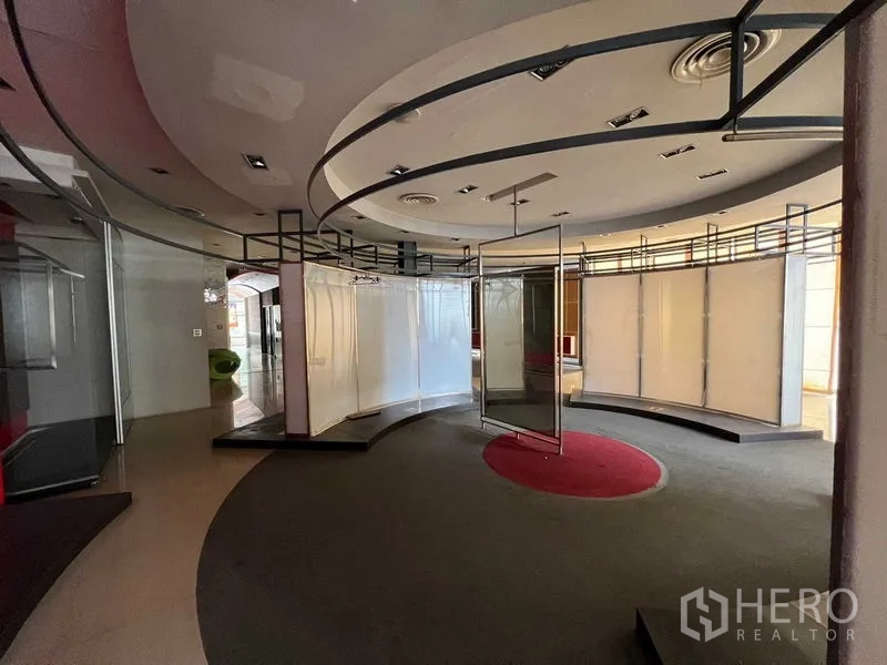 Retail Space for rent - Curved partitioned display area with ceiling railings and a central carpeted circle.