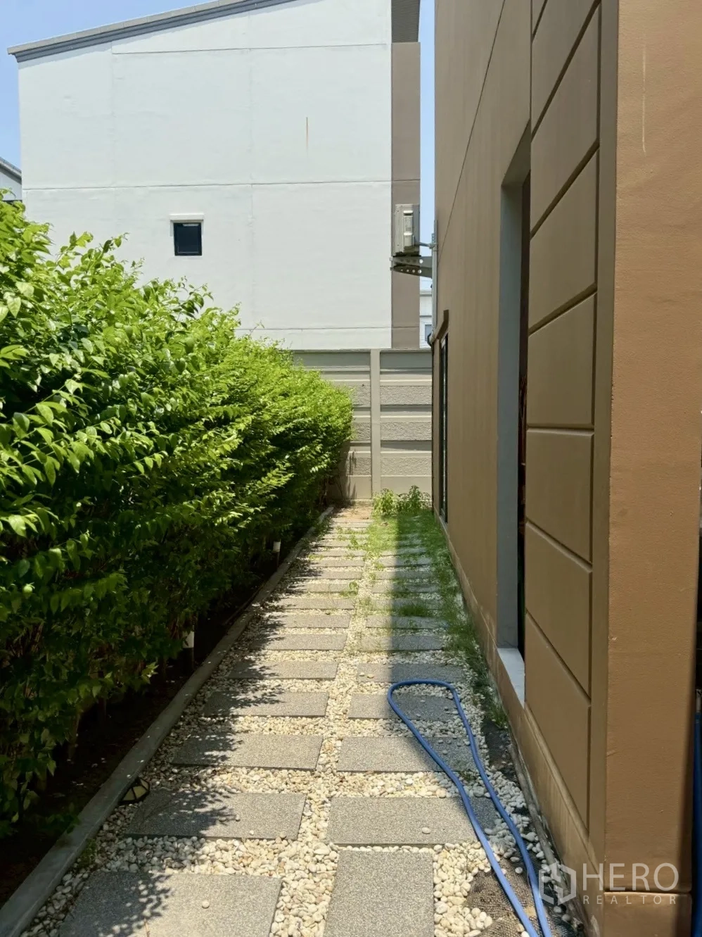 Townhouse for rent in Prawet, Bangkok - Side garden walkway with stepping stones, gravel and hedges.