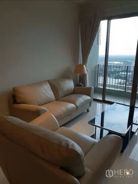 Condominium for rent - Cozy lounge area with sofa set beside sliding glass doors leading to a high-floor balcony and city view.