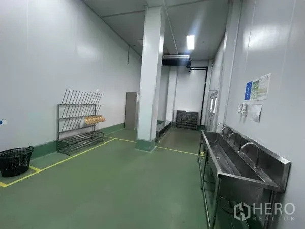 Factory for rent - Hygiene zone with long stainless-steel wash sinks, storage racks, and clearly marked floor lines in the cleanroom.