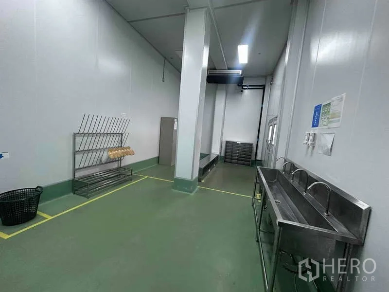 Factory for rent - Hygiene zone with long stainless-steel wash sinks, storage racks, and clearly marked floor lines in the cleanroom.