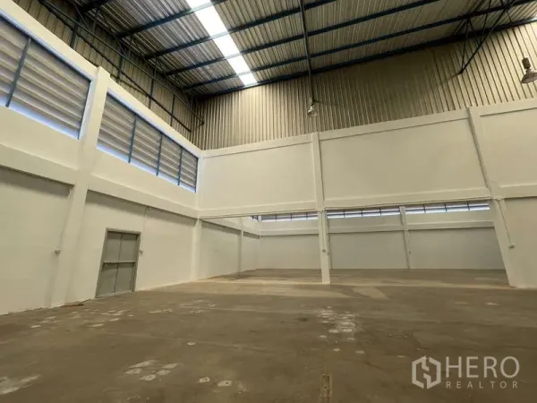 Factory for rent in Ban Phaeo, Samut Sakhon - Clear-span production floor with skylights, tall walls and an emergency door.