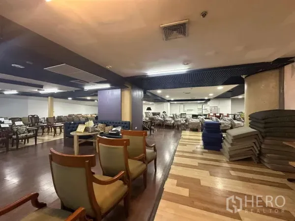Retail Space for rent - Open-plan retail showroom with mixed wood flooring, columns, grid ceiling and ceiling lights, set up with furniture displays.