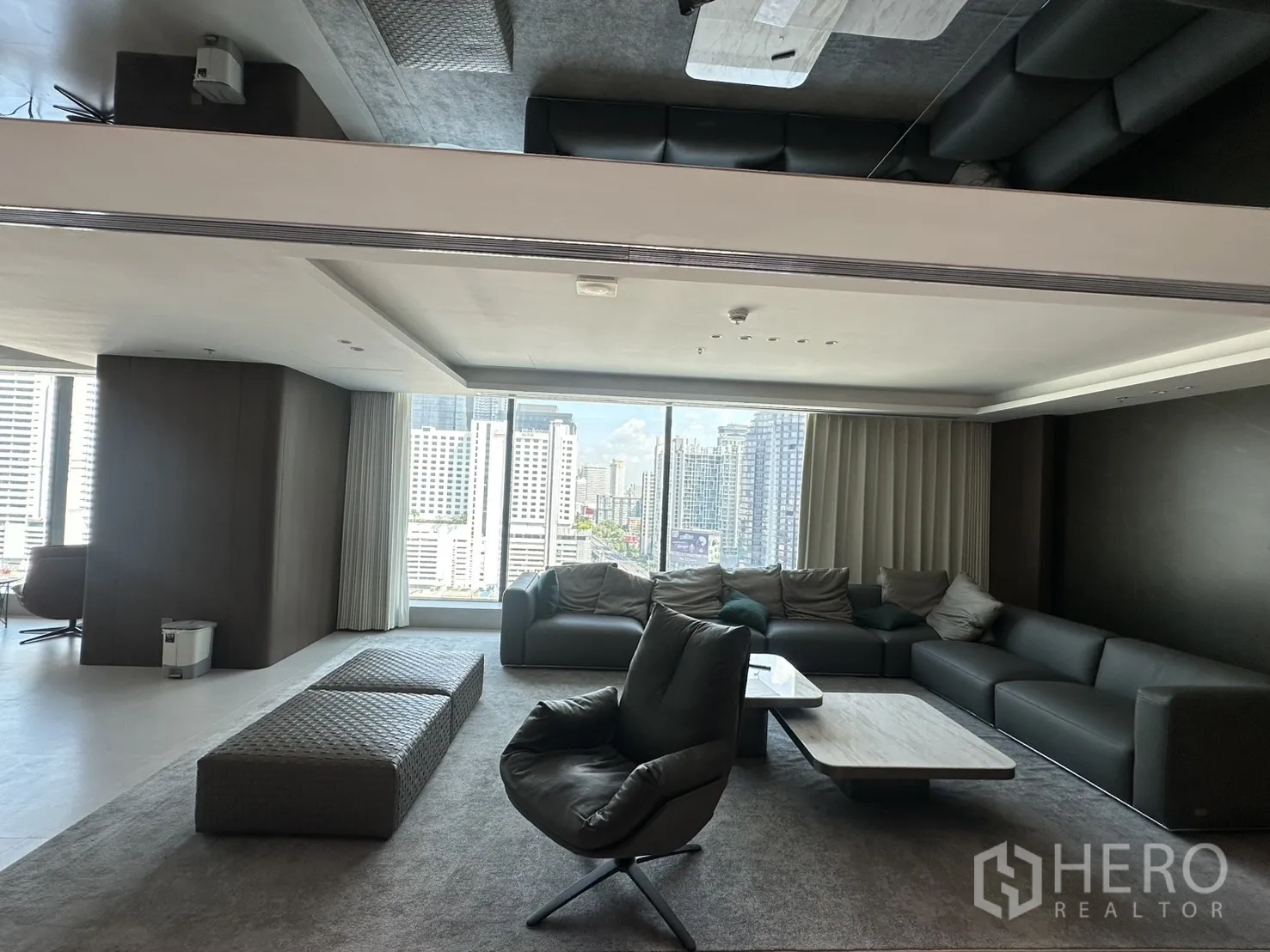 Office Space for rent in Din Daeng, Bangkok - Lounge area with sectional sofa, armchairs, and a coffee table facing city views.