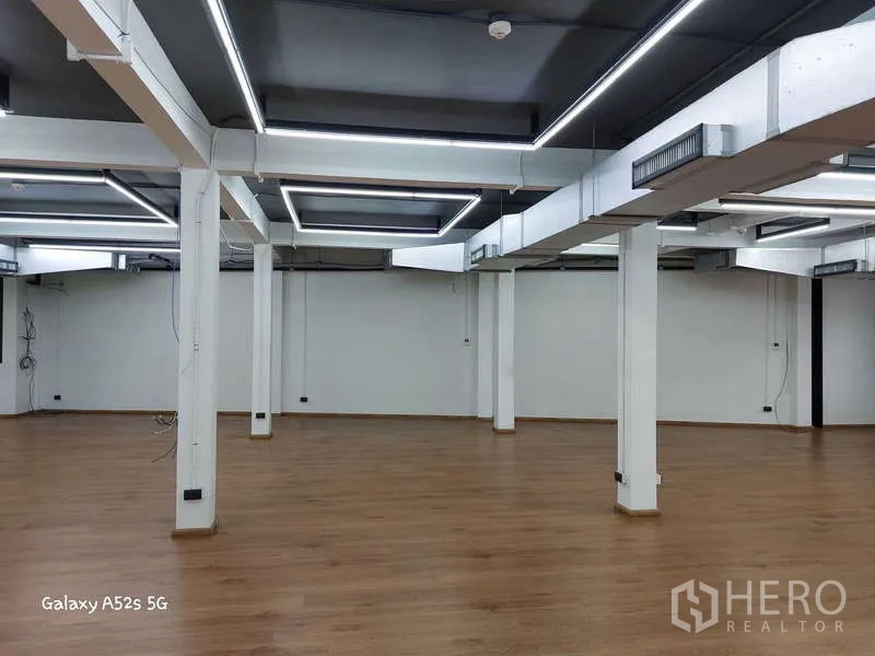 Office Space for rent in Khlong Toei, Bangkok - Large open office with square LED light frames on a dark ceiling and support columns.