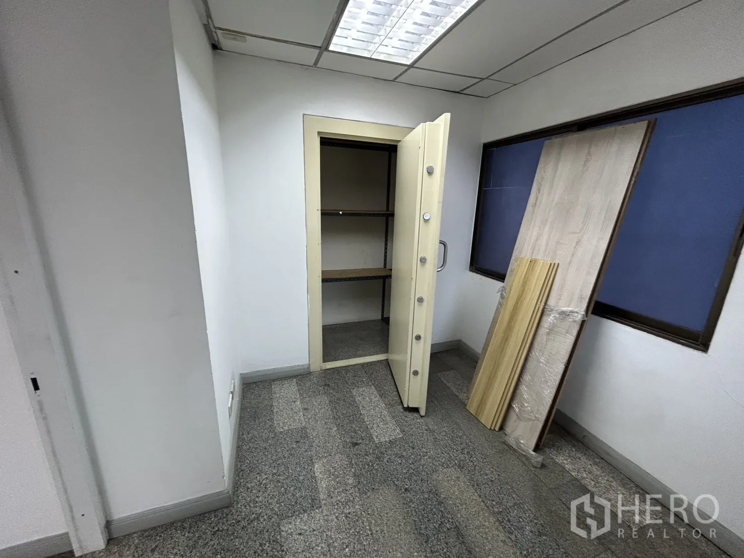 Office Space for rent in Khlong Toei, Bangkok - Small storage room with a heavy-duty safe door, shelving, and window panels.