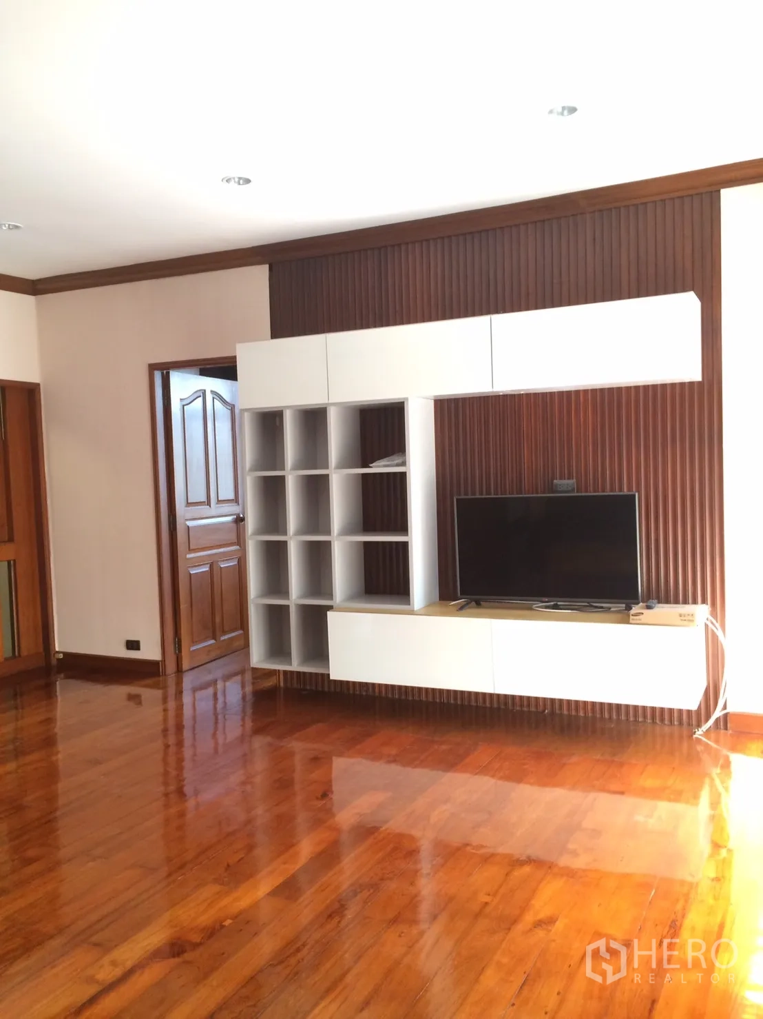 Detached House for rent in Khlong Toei, Bangkok - Family room with built-in media wall, shelving and glossy wood flooring.
