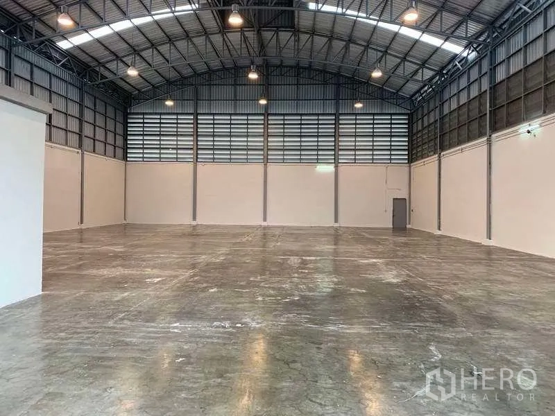 货栈 出租在Bang Phli, Samut Prakan - 对称视角的明亮仓库大厅，天窗采光与钢架屋顶。