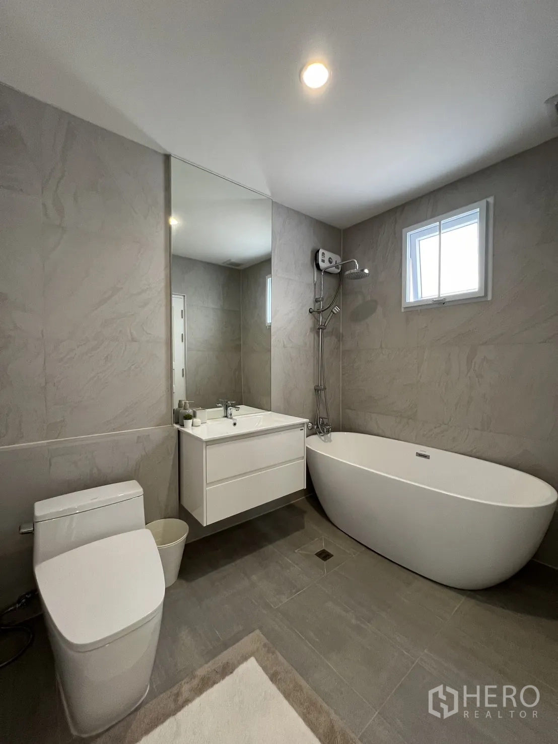 Detached House for rent in Mueang Samut Prakan, Samut Prakan - Bathroom with bathtub, shower and toilet under high windows.