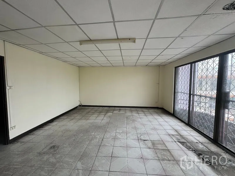 店屋 出租在Watthana, Bangkok - 大开间办公空间，格栅吊顶、瓷砖地和带防护网的窗户。