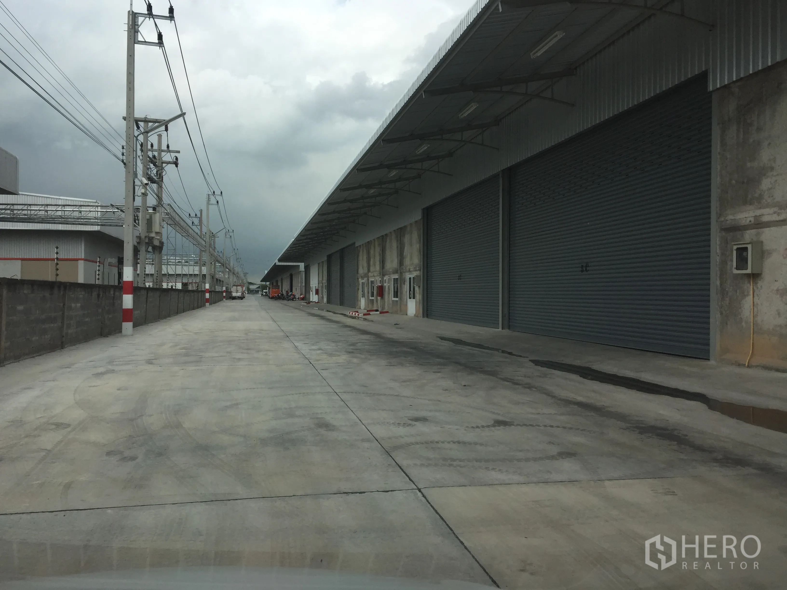货栈 出租在Lam Luk Ka, Pathum Thani - 外部车道配长雨棚与多樘大型卷帘门，卡车通行便捷。