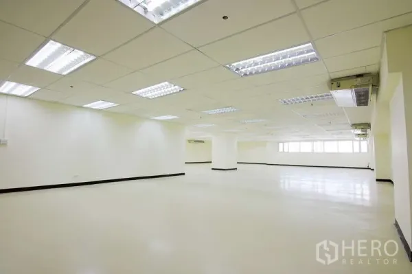 Office Space for rent - Spacious office floor with central column, bright lighting, and wide side windows.