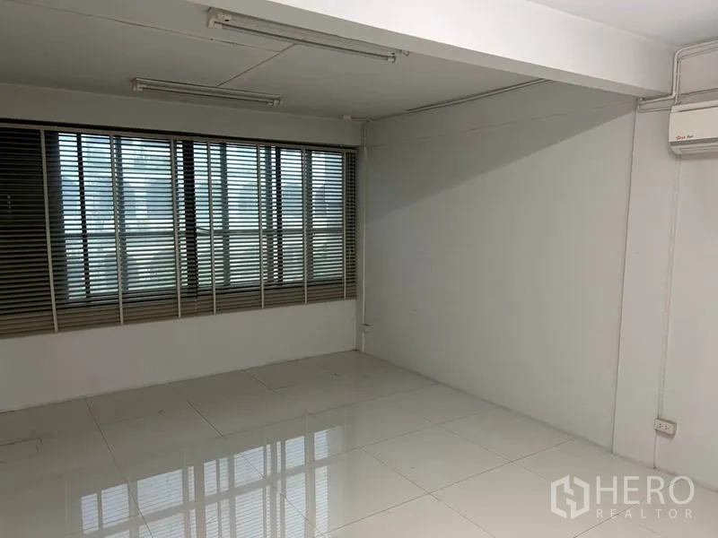 Shophouse for rent in Bang Rak, Bangkok - Room with wide windows and blinds, white tiled floor and wall-mounted air conditioner.