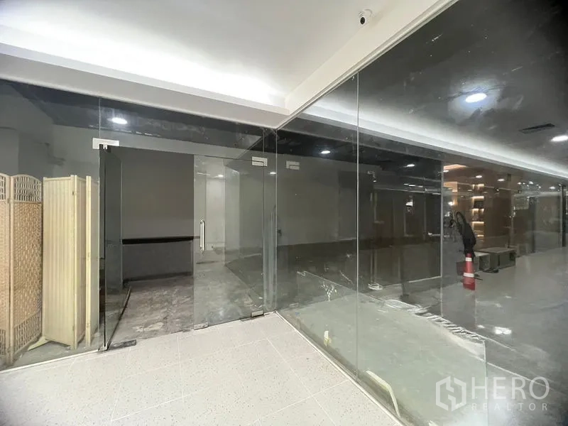 Retail Space for rent in Khlong Toei, Bangkok - Frameless glass shopfront with double doors opening to a vacant retail unit along a bright corridor.
