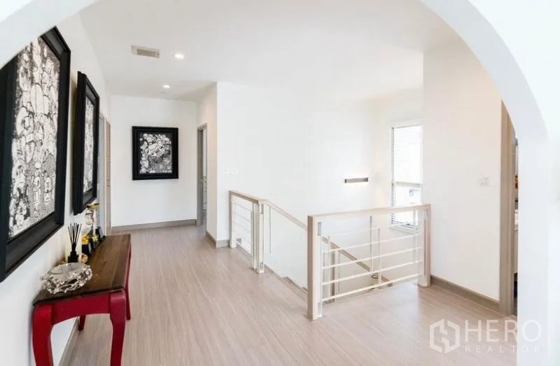 Detached House for rent - Upper hallway with arched entry, wood floors, stair railing, and framed artwork along the wall.