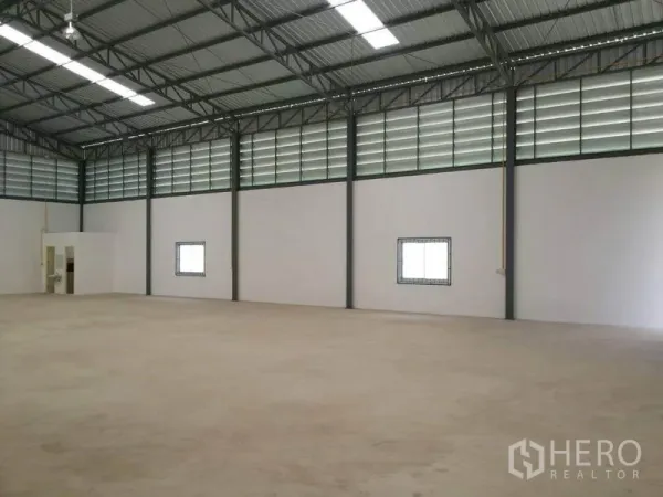 Warehouse for rent in Lam Luk Ka, Pathum Thani - Open storage hall showing ventilation panels, small windows, and a built‑in bathroom area.
