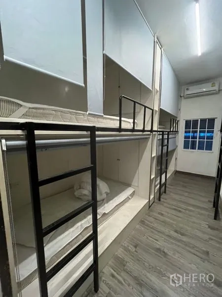 Shophouse for rent or sale in Watthana, Bangkok - Long dormitory room featuring several built‑in bunks, ladders and an air conditioner.