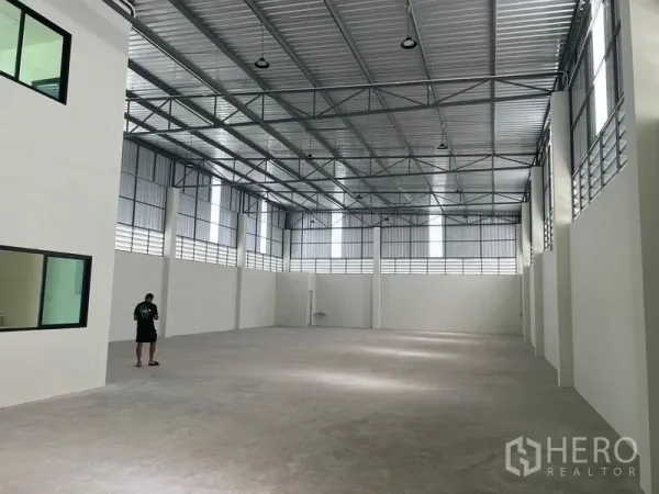 Warehouse for rent in Bang Phli, Samut Prakan - Spacious high‑bay warehouse interior with steel truss roof, clerestory windows and polished concrete floor.