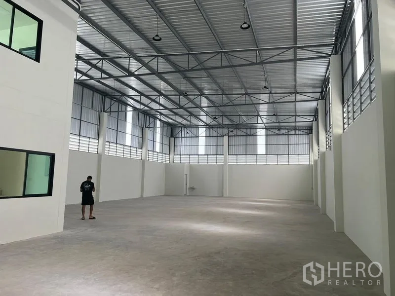 Warehouse for rent in Bang Phli, Samut Prakan - Spacious high‑bay warehouse interior with steel truss roof, clerestory windows and polished concrete floor.