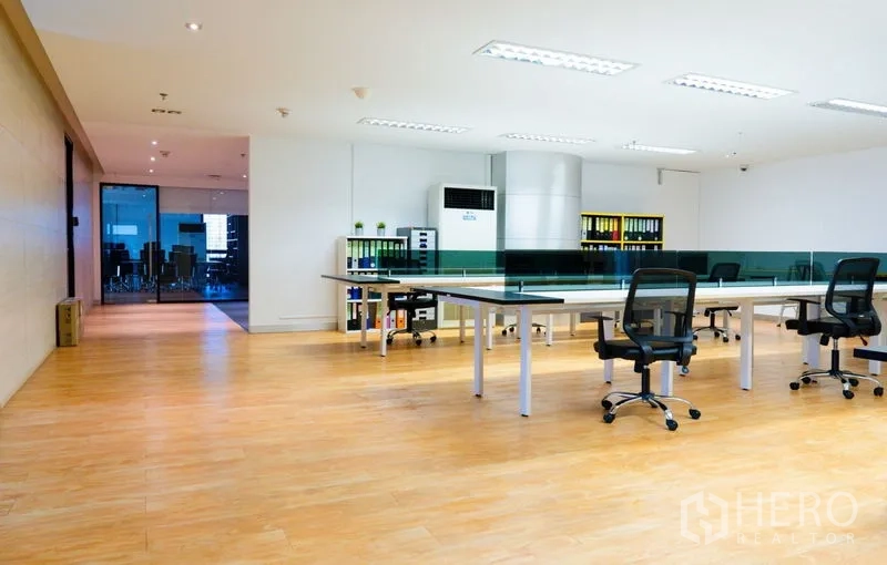 Office Space for rent - Large open workspace with shared desks, filing shelves and a glass meeting room.