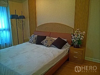 Condominium for rent in Pathum Wan, Bangkok - Primary bedroom of Pathum Wan condo featuring an upholstered headboard, bedside cabinet, and window with sheer curtains.
