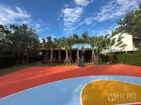 Land for rent in Watthana, Bangkok - Wide view of private outdoor basketball half-court with palms and lawn on a Sukhumvit land parcel.