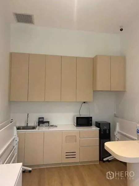 Office Space for rent in Huai Khwang, Bangkok - Compact office pantry with beige cabinets, sink, microwave and refrigerator.