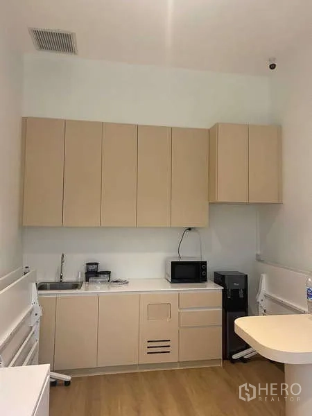 Office Space for rent in Huai Khwang, Bangkok - Compact office pantry with beige cabinets, sink, microwave and refrigerator.