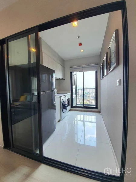 Condominium for sale in Khlong Toei, Bangkok - Separate kitchen behind sliding glass door with fridge, washer, and balcony city view.
