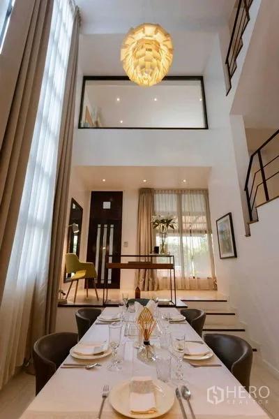 带办公室的家 出售在Watthana, Bangkok - 挑高餐厅配吊灯、夹层与楼梯的现代住办合一空间。