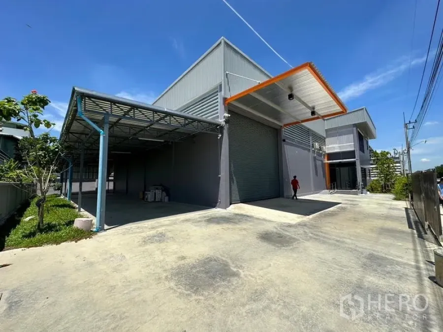 Factory for rent or sale in Lam Luk Ka, Pathum Thani - Another angle of the factory exterior showing roller shutter, canopy and spacious yard.