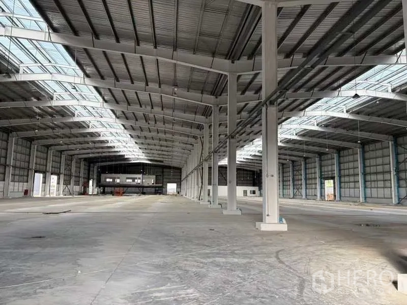 Factory for rent in Rayong - Open-plan factory floor with wide bays, concrete surface and natural light from roof panels.