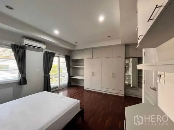 Townhouse for rent in Khlong Toei, Bangkok - Spacious bedroom with built-in wardrobes, work desk, balcony doors and air conditioning.
