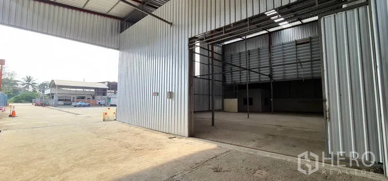 Warehouse for rent in Pak Kret, Nonthaburi - Wide metal-clad warehouse with large sliding door and open yard in Pak Kret, Nonthaburi.