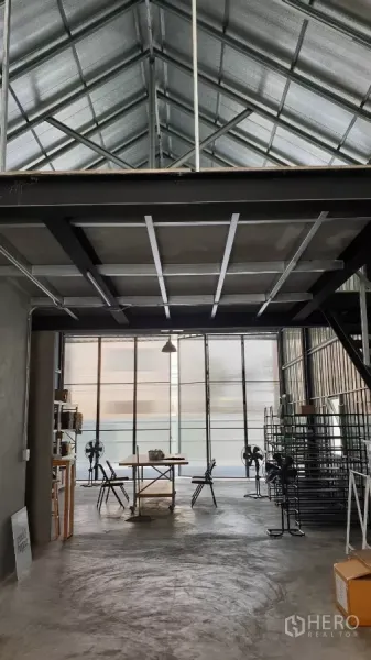 Warehouse for rent in Chatuchak, Bangkok - High-ceiling warehouse workspace with front glass panels, racks and a table.