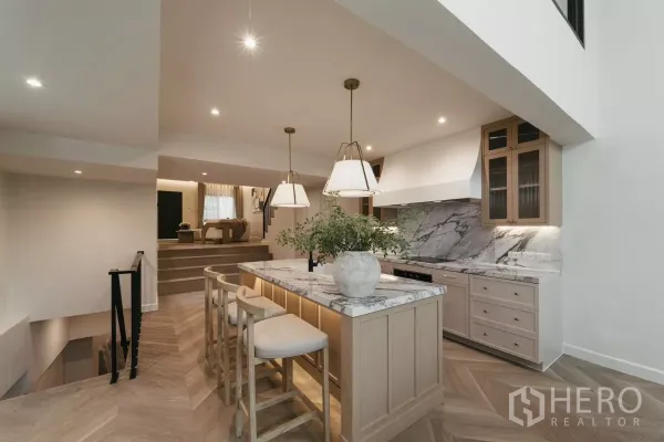 Townhouse for rent in Watthana, Bangkok - Open-plan marble island kitchen with pendant lights and split-level living area.