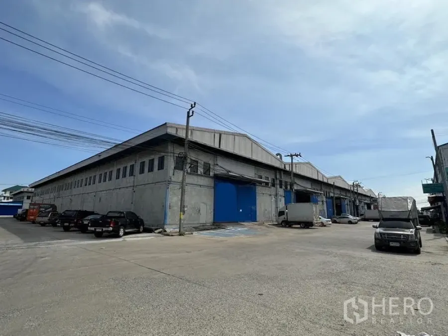 货栈 出租在Bang Phli, Samut Prakan - 邦普里大型混凝土仓库外观，蓝色装卸门与宽阔车道，位于北榄府。