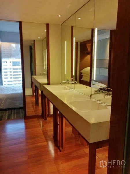 Condominium for rent in Pathum Wan, Bangkok - Modern bathroom vanity with twin sinks, large mirrors and warm lighting.