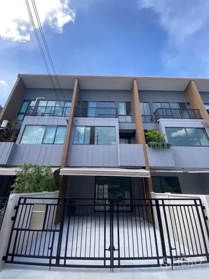 Townhouse for rent in Prawet, Bangkok - Modern three-storey townhouse facade with gated parking area.