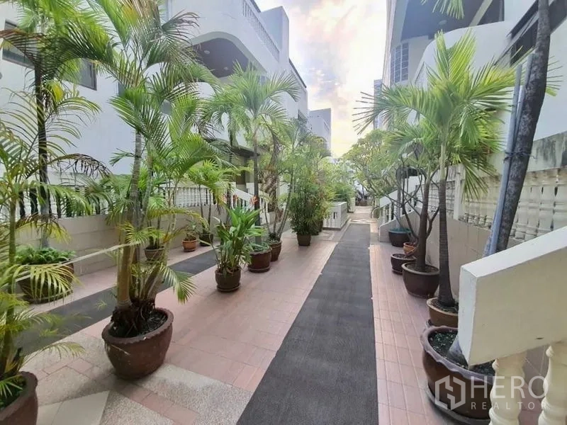 Townhouse for rent in Sathon, Bangkok - Leafy pedestrian walkway between townhouse blocks lined with potted palms.