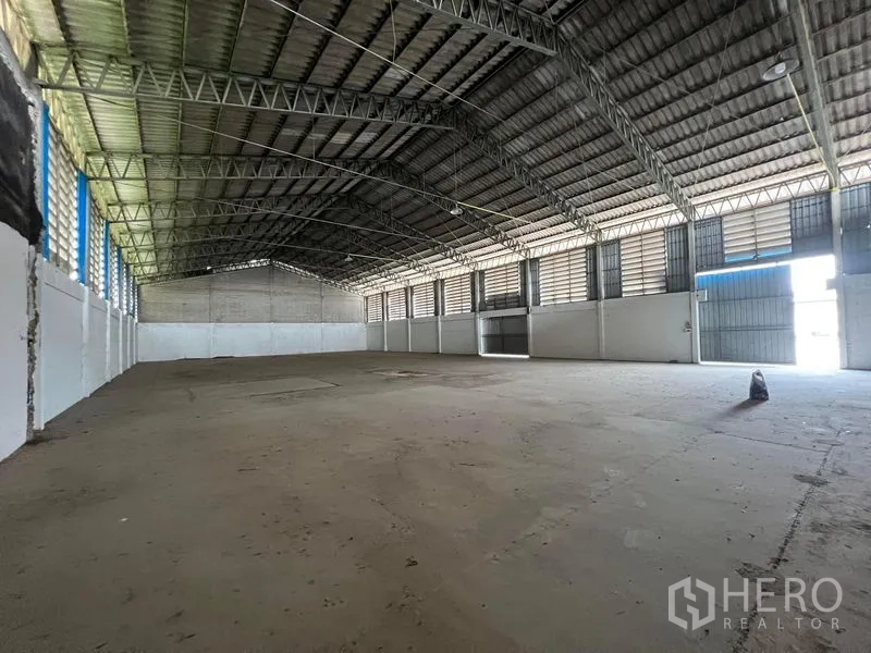 Warehouse for rent in Bang Pa-in, Phra Nakhon Si Ayutthaya - Empty warehouse space with high roof, louvered windows and an open sliding gate.