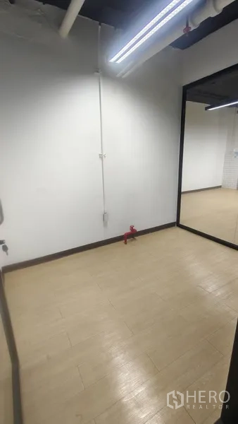 Office Space for rent in Pathum Wan, Bangkok - Compact room with light wood-look floor and a large mirror wall, suitable for storage or phone booth.
