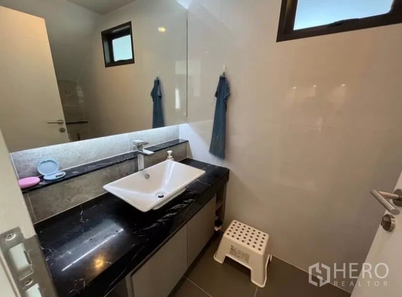 Detached House for rent in Prawet, Bangkok - Modern bathroom with a vessel sink on black stone vanity and a large mirror.