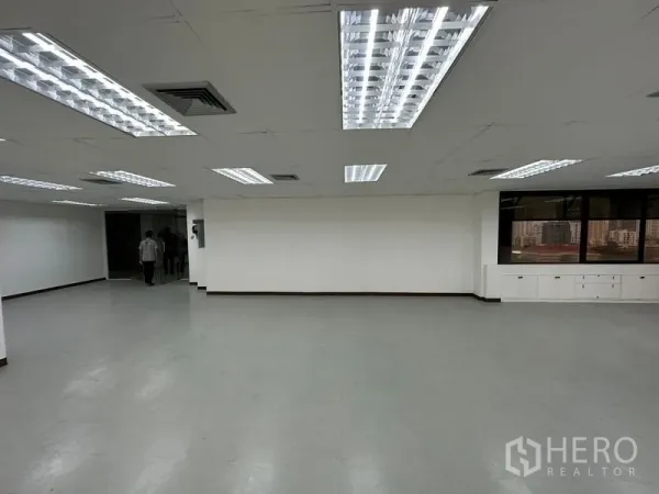 Office Space for rent in Watthana, Bangkok - Open office area with white walls, recessed lighting, corner windows with urban views and built-in storage.